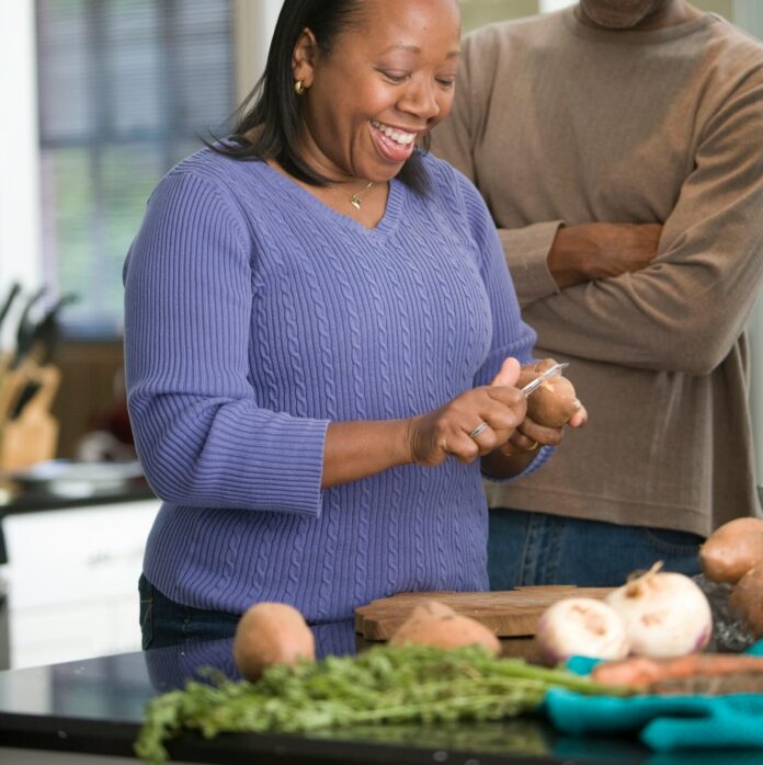Woman peeling vegetables next to husband.