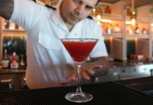This Pomegranate Martini Comes Just in Time For Summer Bartender pouring a martini