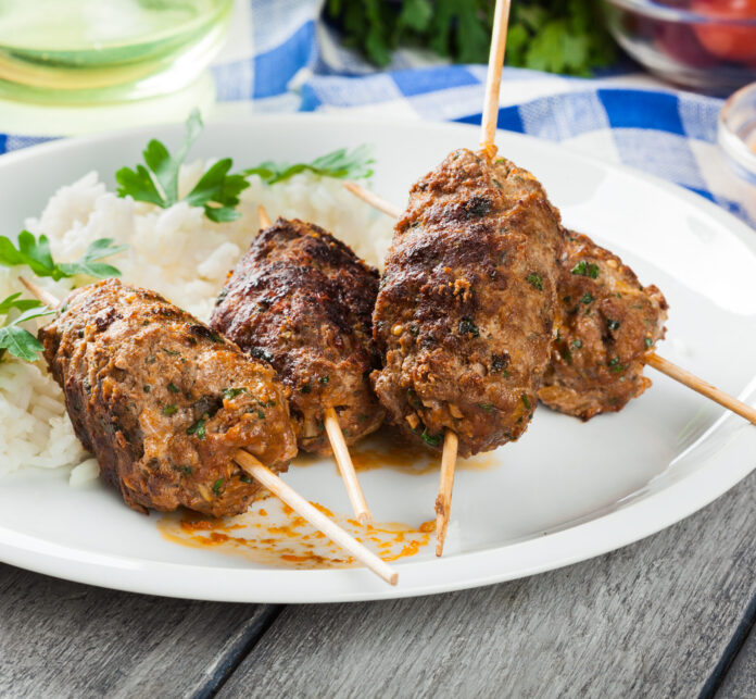Barbecued kofta with rice on a plate.