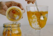 3 Ways to Incorporate Turmeric Into Your Meals Crop hands adding turmeric in glass of hot water in morning